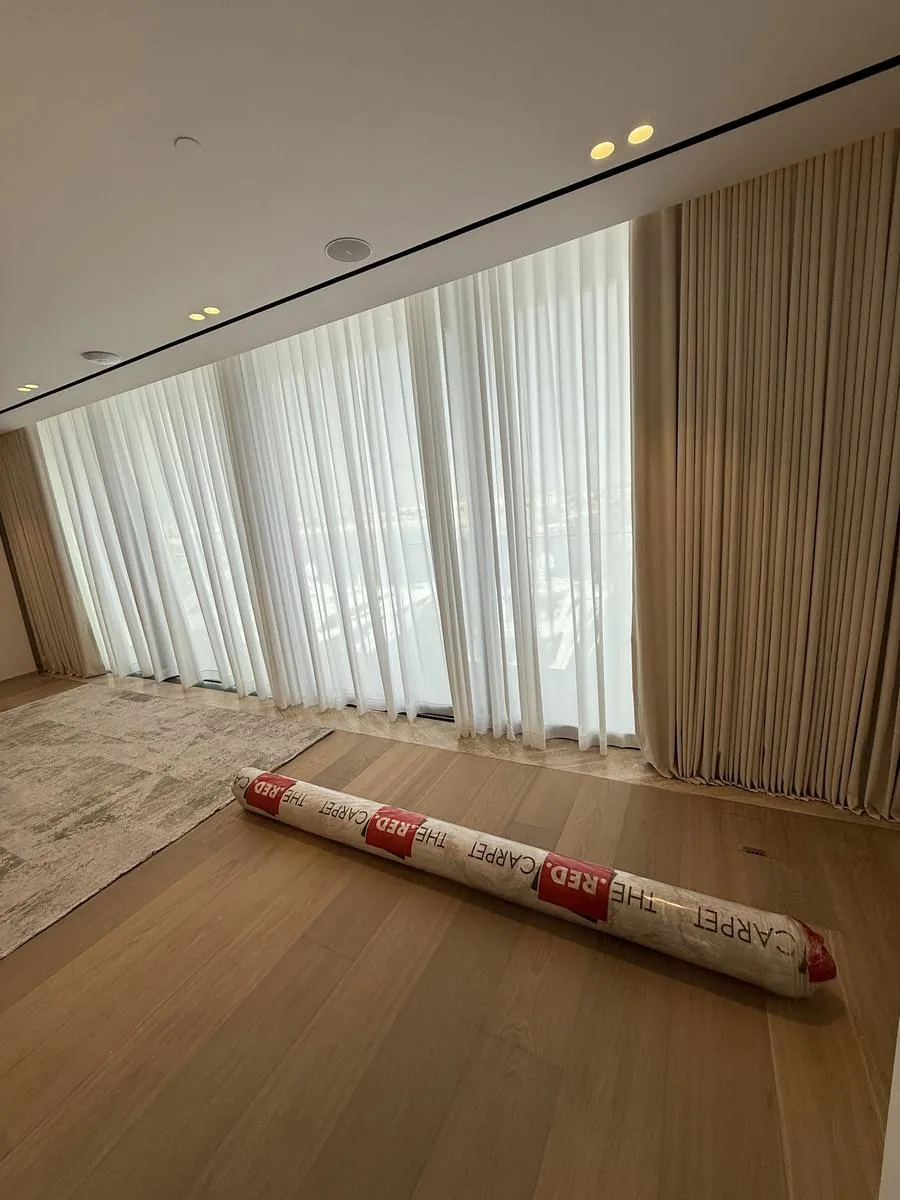Black blackout curtains layered over white sheers on a floor-to-ceiling Dubai window