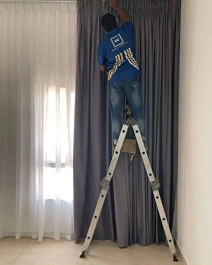 Dubai Curtain installer fitting curtains on a ladder